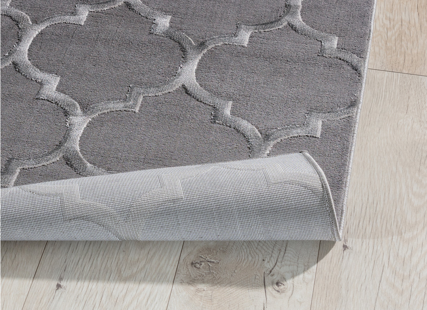 Dywan Elsher Grey 120x180 cm z lekko podwiniętą krawędzią – prezentacja spodniej warstwy i gęstego splotu materiału.