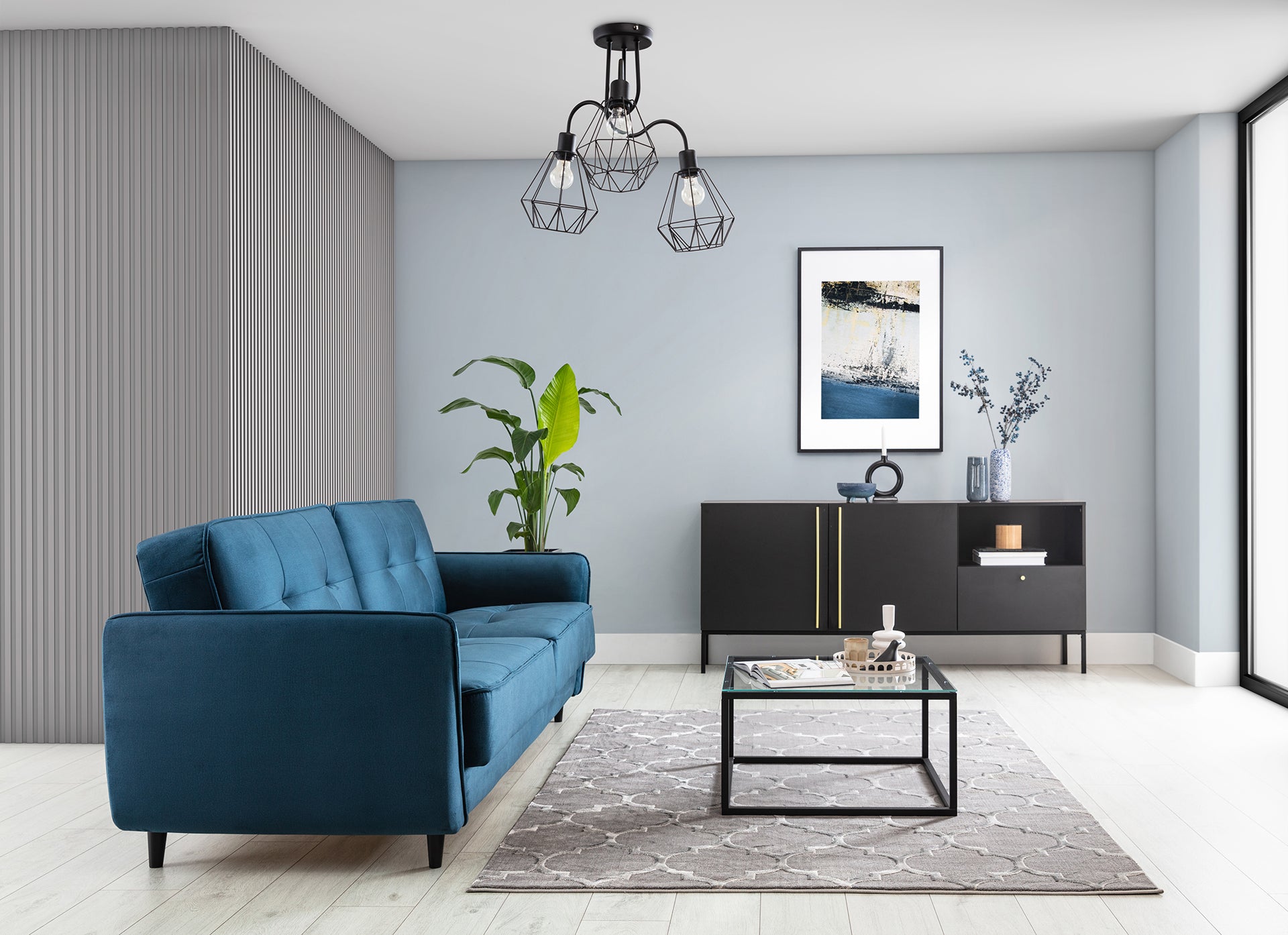 Dywan Elsher Grey 160x220 cm w przestronnym, jasnym salonie z granatową kanapą, czarną komodą i zieloną rośliną doniczkową – aranżacja w nowoczesnym stylu.