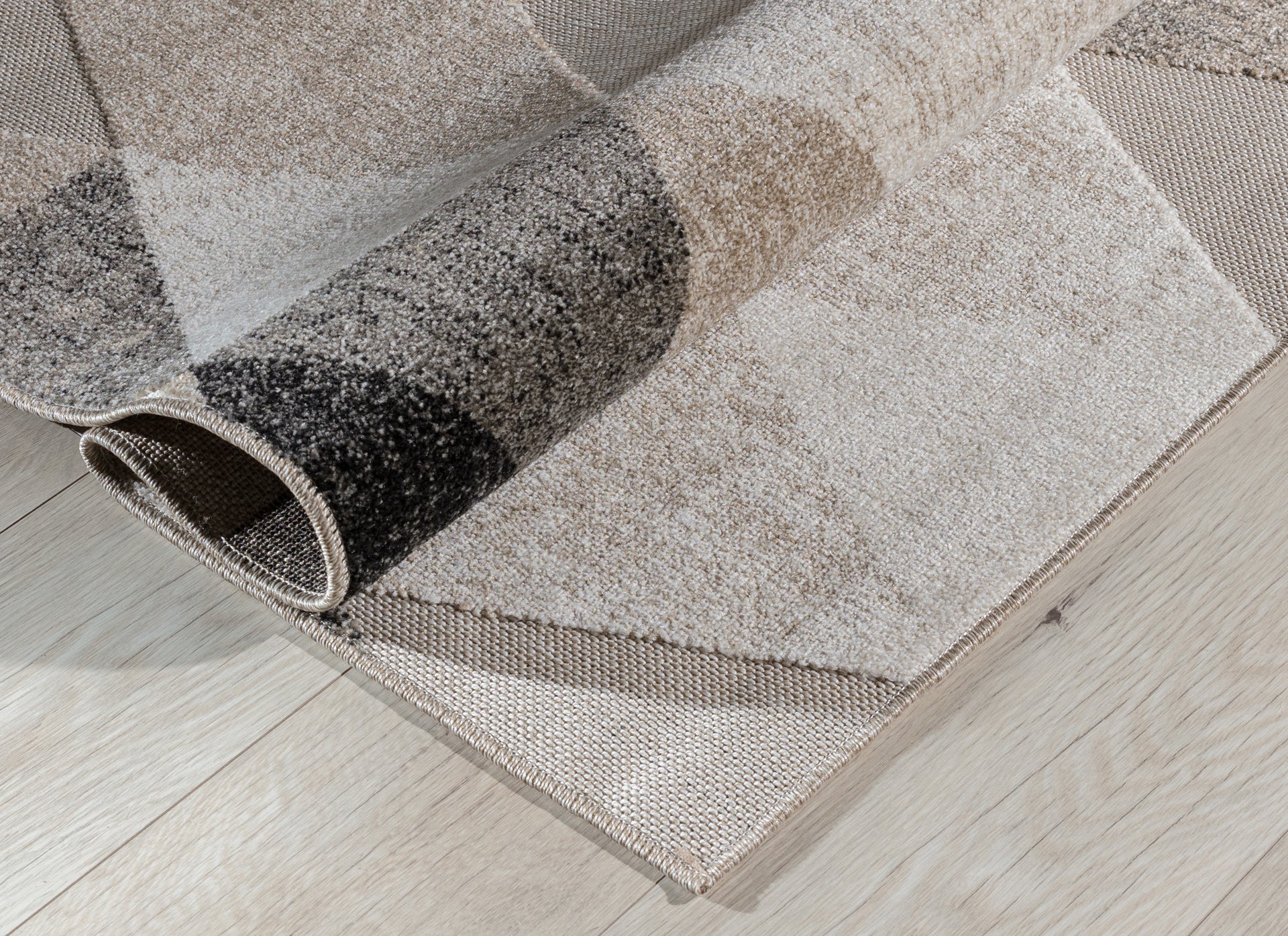 Dywan Eustache Beige 80x150 cm zwinięty w rulon – widoczna grubość i splot materiału z geometrycznym wzorem.