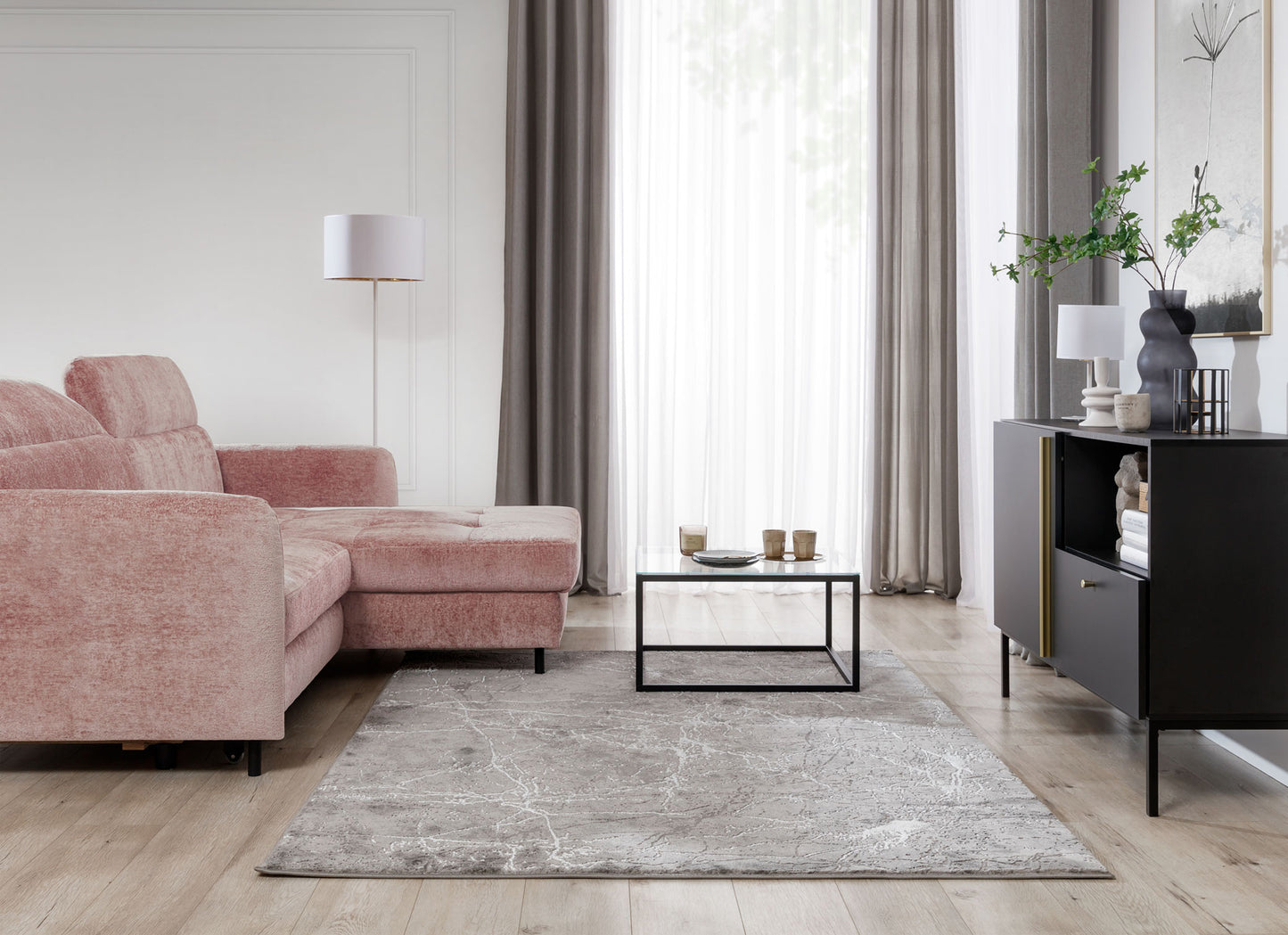 Dywan Siggi Grey 120x180 cm w jasnym salonie z różowym narożnikiem i dużymi oknami – elegancka aranżacja w pastelowych tonach.