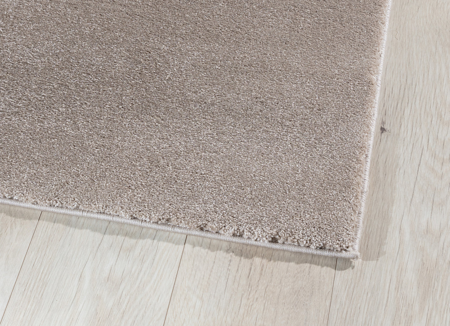 Zbliżenie na róg dywanu Verlice Beige 80x150 cm – gęste, miękkie włókno i precyzyjnie wykończone krawędzie.