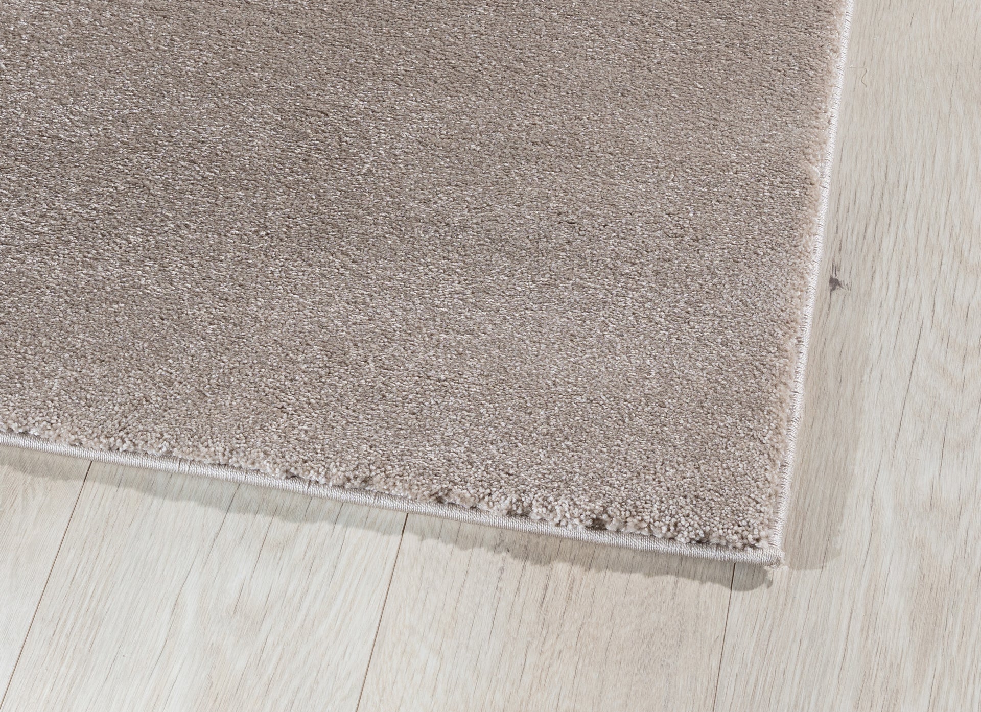 Zbliżenie na róg dywanu Verlice Beige 80x150 cm – gęste, miękkie włókno i precyzyjnie wykończone krawędzie.