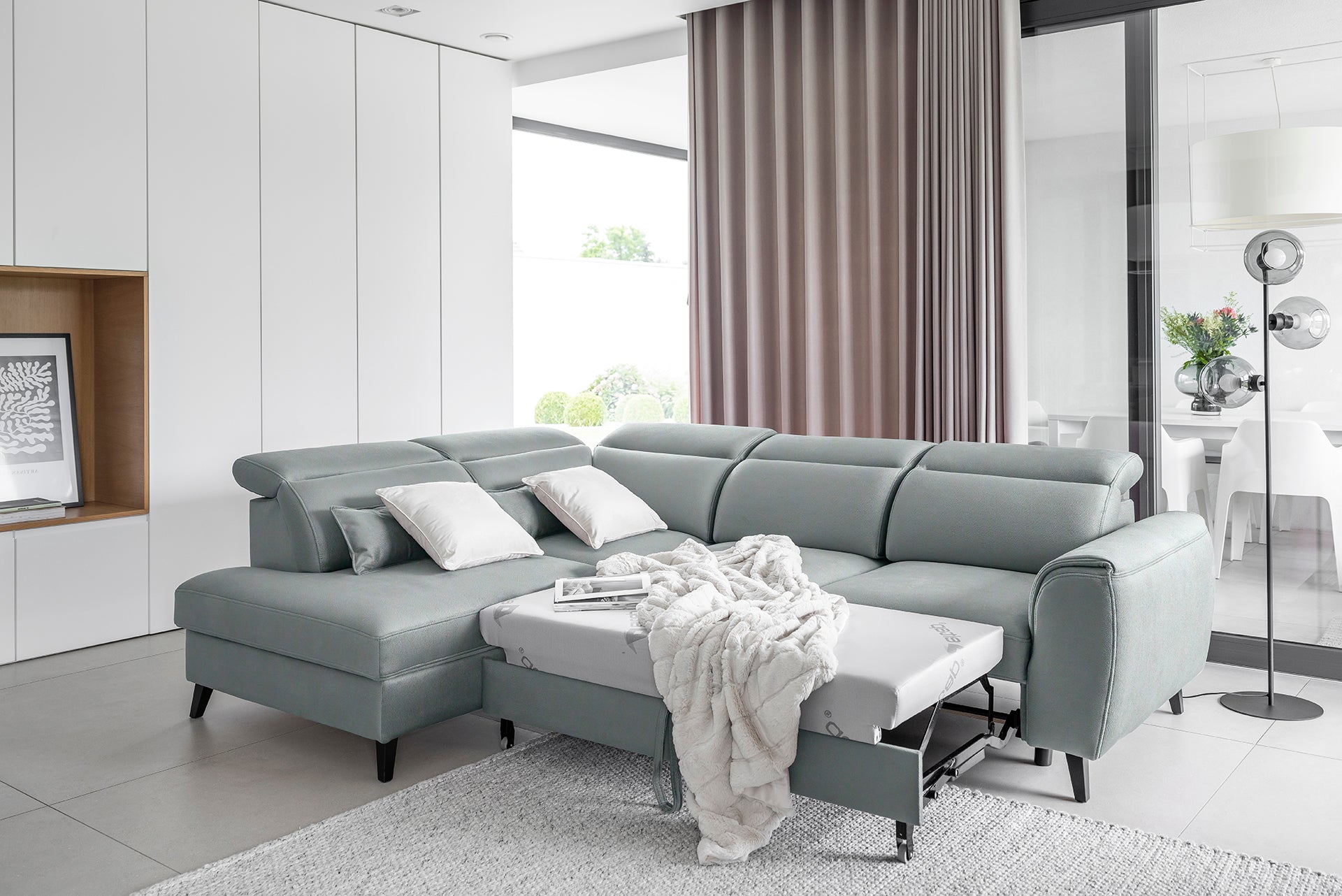 Lewostronny narożnik Noble w tkaninie Savoi 100 o subtelnym szarym odcieniu i nowoczesnej bryle. Designerski narożnik do salonu idealny do jasnych, przestronnych i współczesnych aranżacji wnętrz.