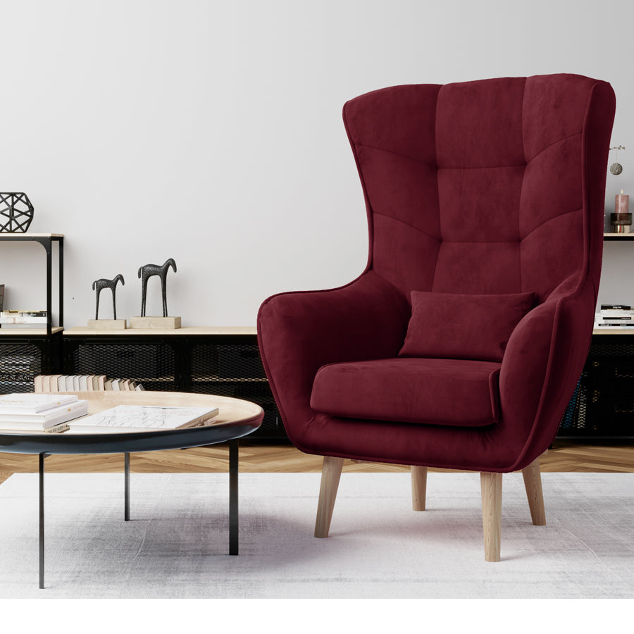 Fotel Arti w kolorze Matt Velvet 68 bordowy w stylowym salonie, ustawiony przy stoliku kawowym na jasnym dywanie.