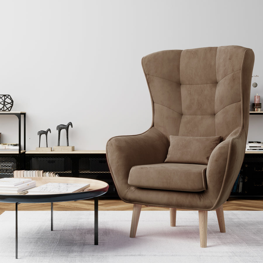 Fotel Arti w kolorze Monolith 09 jasnobrązowy ustawiony w nowoczesnym salonie z jasną ścianą, stolikiem i dekoracjami.