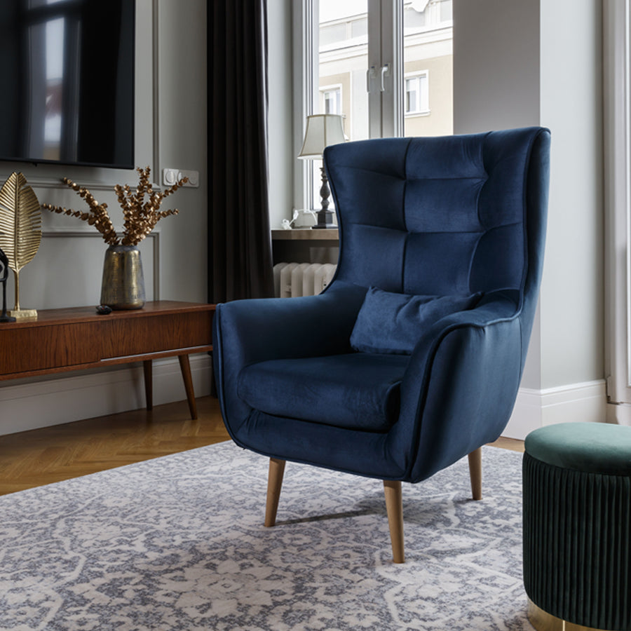 Fotel Arti w kolorze Monolith 77 granatowy w eleganckim salonie, ustawiony przy stoliku kawowym na jasnym dywanie.