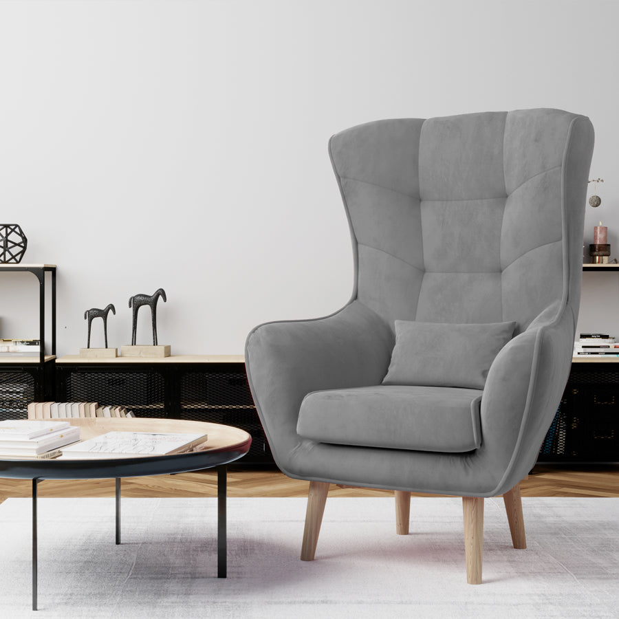 Fotel Arti w kolorze Monolith 84 jasnoszary w nowoczesnym salonie, ustawiony przy stoliku kawowym na jasnym dywanie.