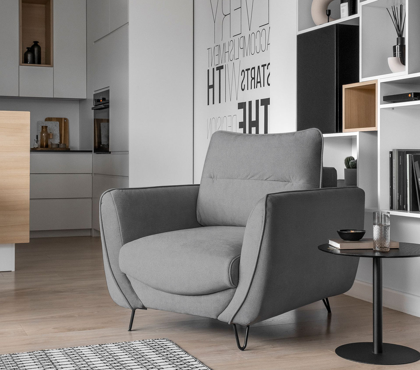 Fotel Silva w kolorze Sola 04 jasnoszary w eleganckim salonie, ustawiony przy stoliku kawowym w jasnym, minimalistycznym wnętrzu.