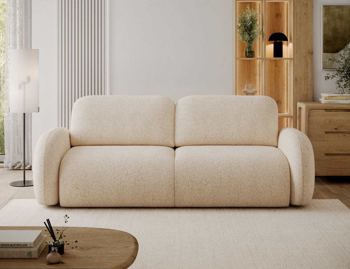 Kanapa Avuela w jasnobeżowym kolorze ustawiona w jasnym salonie, widok na wprost z szerokim siedziskiem i zaokrąglonymi podłokietnikami