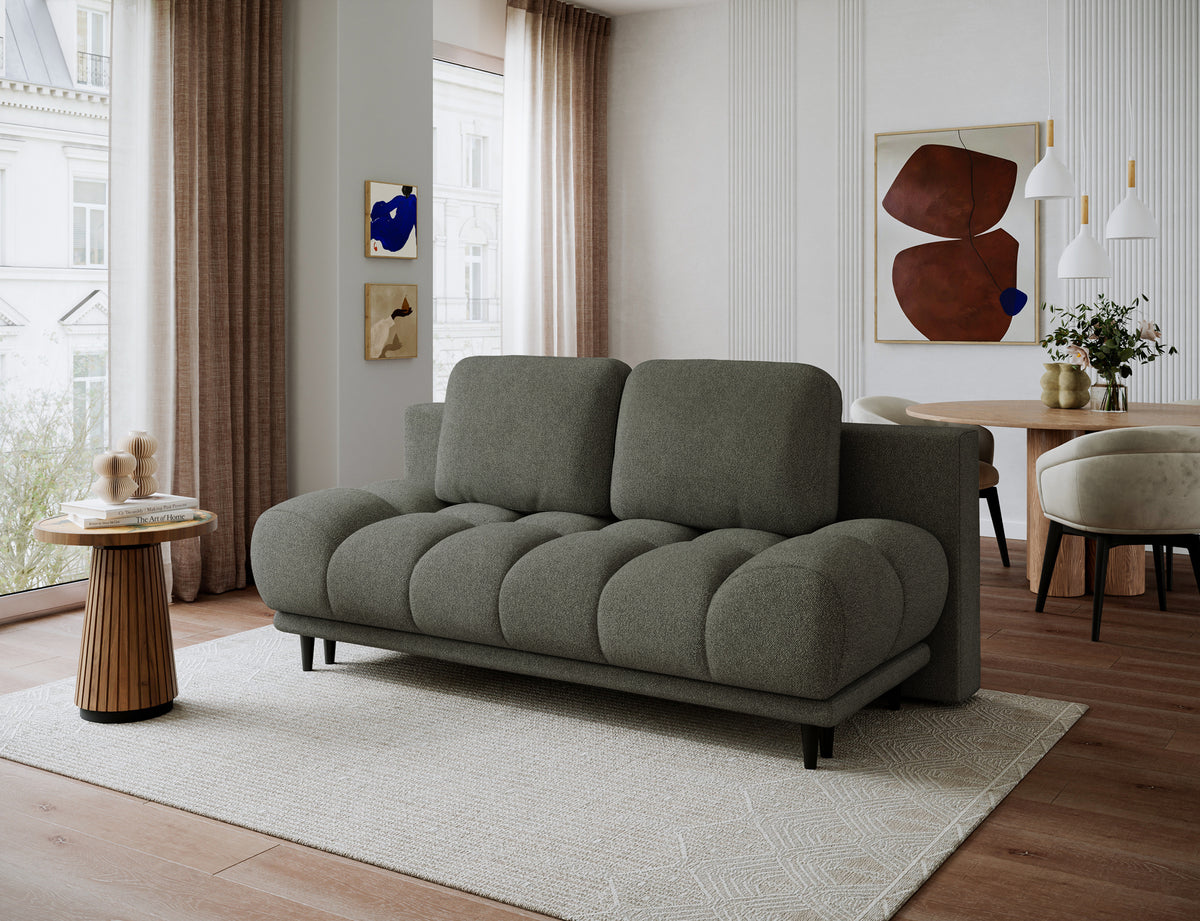 Jasnozielona kanapa Guavio w jasnej aranżacji salonu, ujęcie pod kątem prezentujące zaokrągloną bryłę, siedzisko i poduszki oparcia