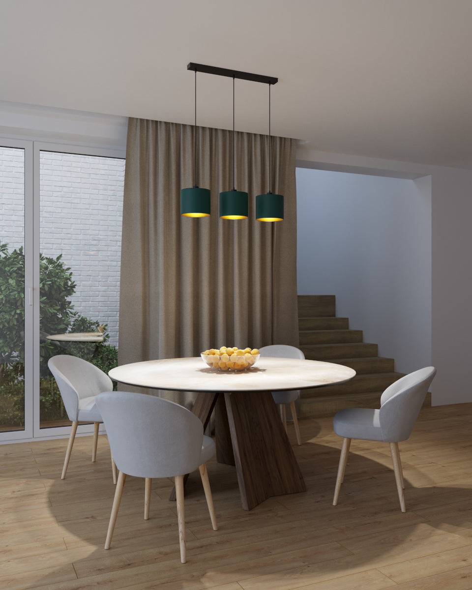Lampa Vespillo 3 z trzema zielono-złotymi abażurami oświetlająca stół jadalny ciepłym, złotym światłem w przytulnie oświetlonym wnętrzu.