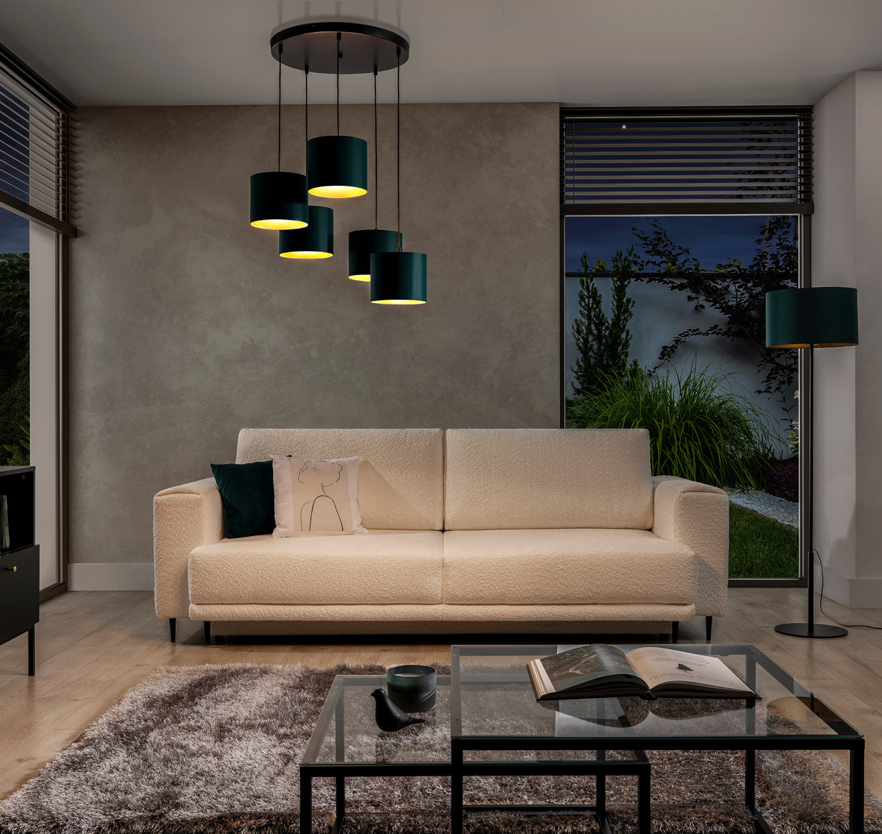 Włączona lampa wisząca Vespillo 5 rzucająca ciepłe, złote światło ku dołowi na kremową sofę i drewniany stolik w przytulnej, wieczornej aranżacji salonu.