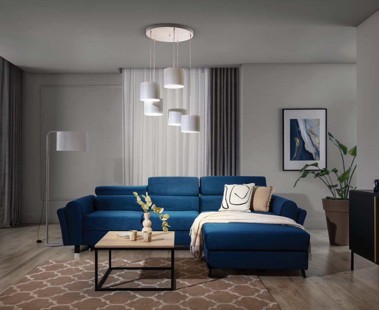 Ten sam salon o zmierzchu, z włączoną lampą sufitową Vespillo 5, która emituje miękkie, ciepłe światło przez pięć abażurów.