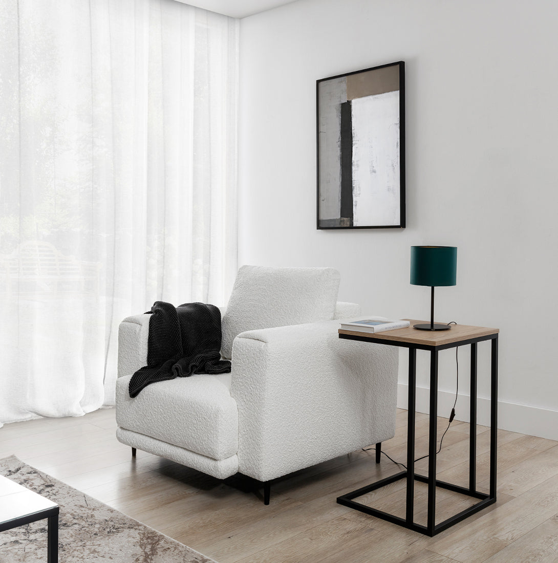 Lampka nocna Vespillo w aranżacji salonu: ustawiona na czarnym stoliku obok białego, bujanego fotela przy dużym oknie w jasnym, minimalistycznym wnętrzu.