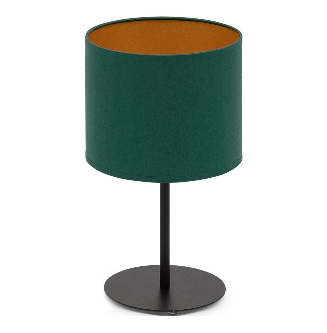 Zielono-złota lampka nocna Vespillo z cylindrycznym abażurem w butelkowej zieleni i metalicznym, złotym wnętrzem, osadzonym na cienkiej, czarnej metalowej nóżce z okrągłą, płaską podstawą, na białym tle.