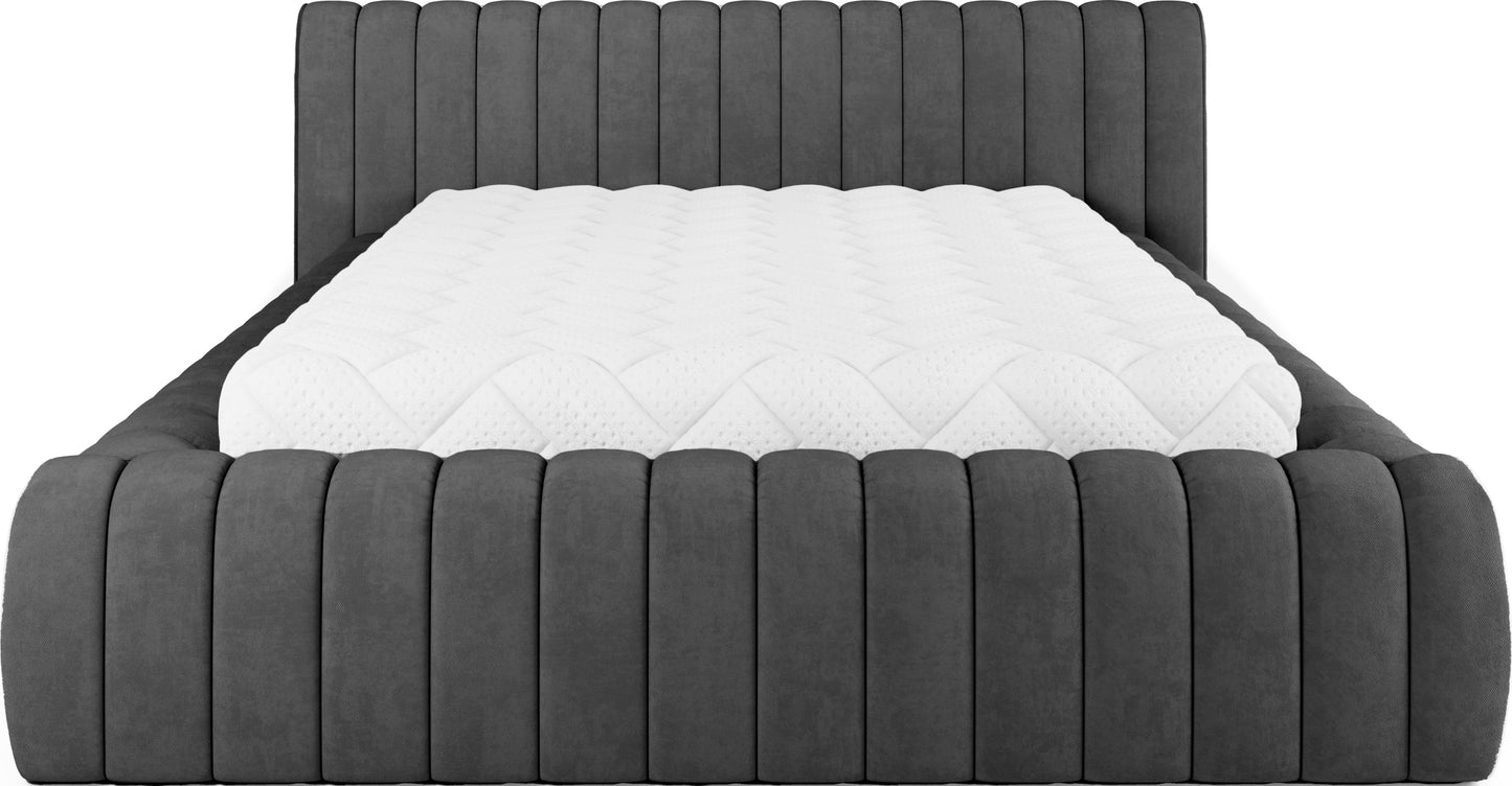 Frontowy widok łóżka tapicerowanego Carilla w tkaninie Sola 06 ciemnoszary z materacem, nowoczesny design z pionowymi przeszyciami.