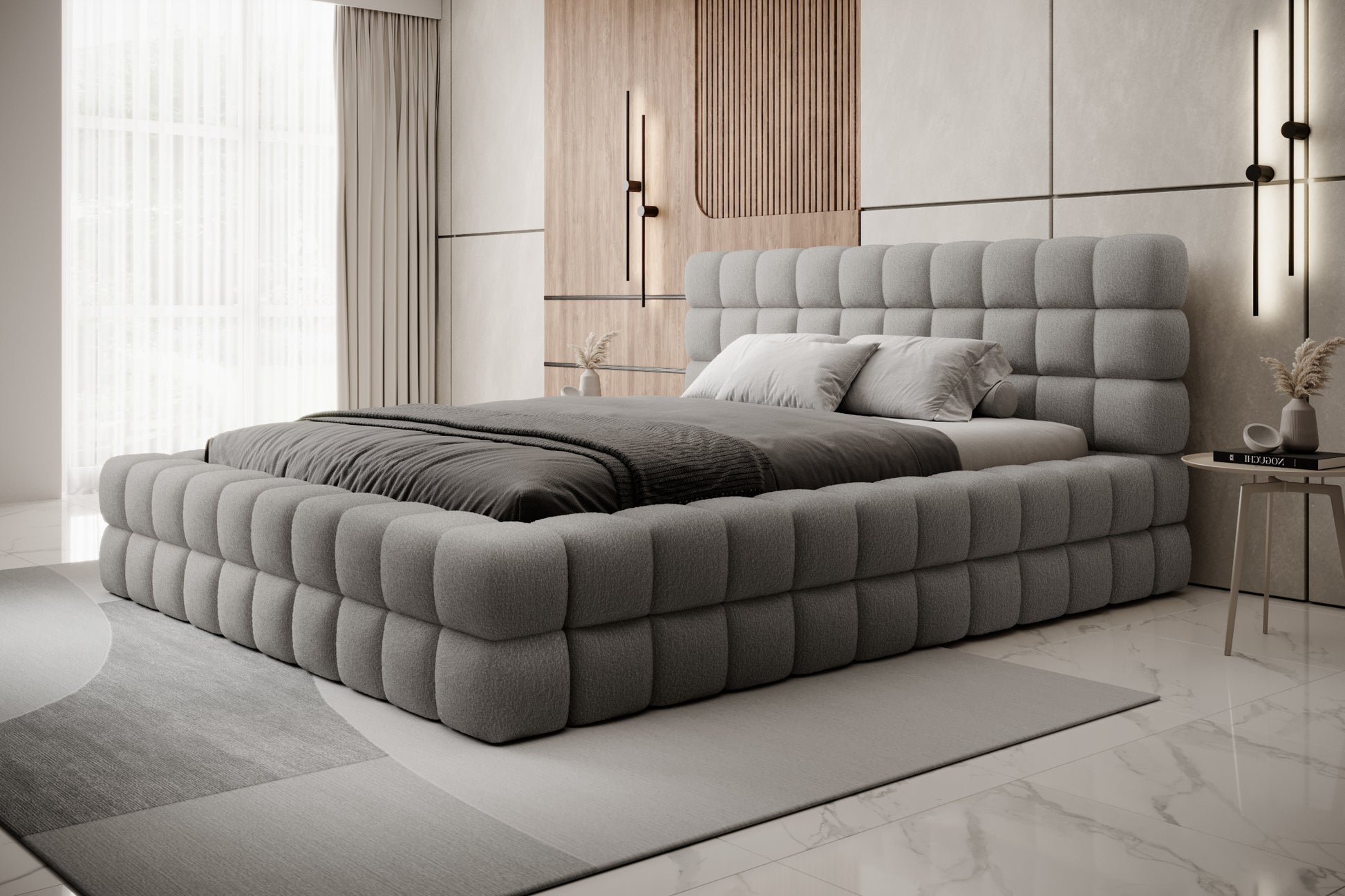 Łóżko tapicerowane Dizzle 180x200 cm w tkaninie Royal 04 szary, ujęcie z boku w jasnym, minimalistycznym wnętrzu z dużymi oknami i szarym dywanem.