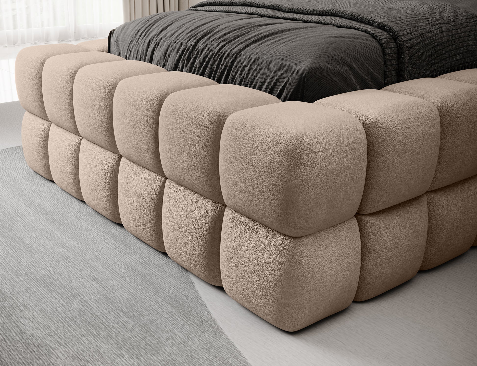 Zbliżenie na narożnik beżowego łóżka Dizzle 90 Amore 18, pokazujące miękkie, pikowane obicie w eleganckiej tkaninie.