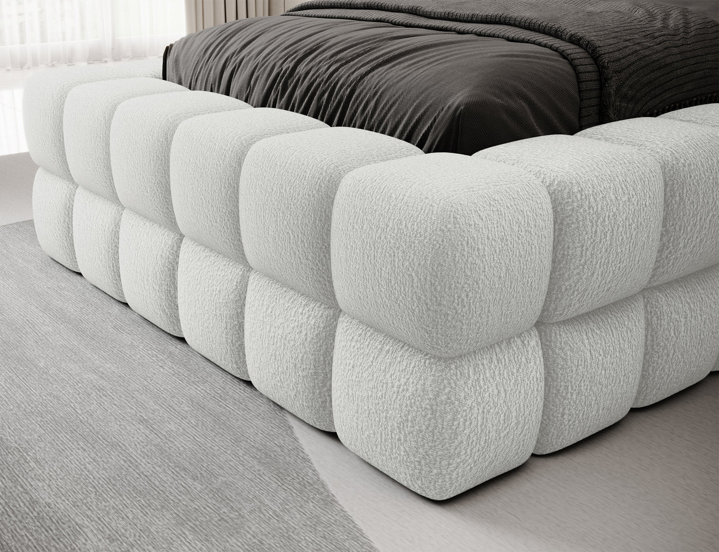 Zbliżenie na bok i narożnik łóżka Dizzle I 90x200 w tkaninie Royal 01 biały, detale pikowanej tapicerki.