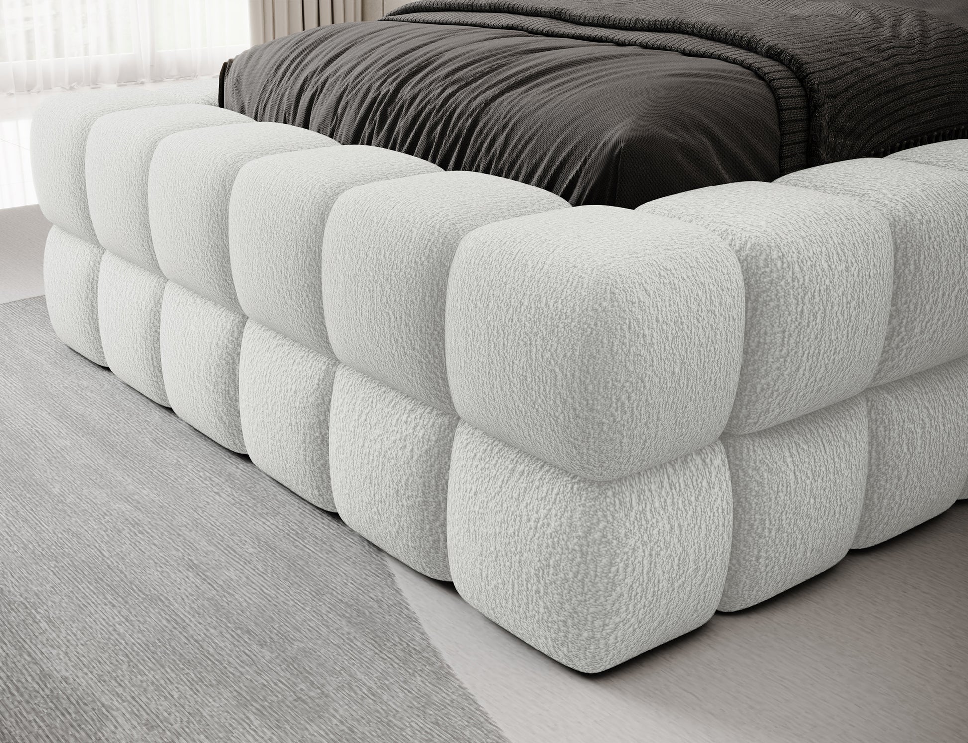 Zbliżenie na bok i narożnik łóżka Dizzle I 90x200 w tkaninie Royal 01 biały, detale pikowanej tapicerki.