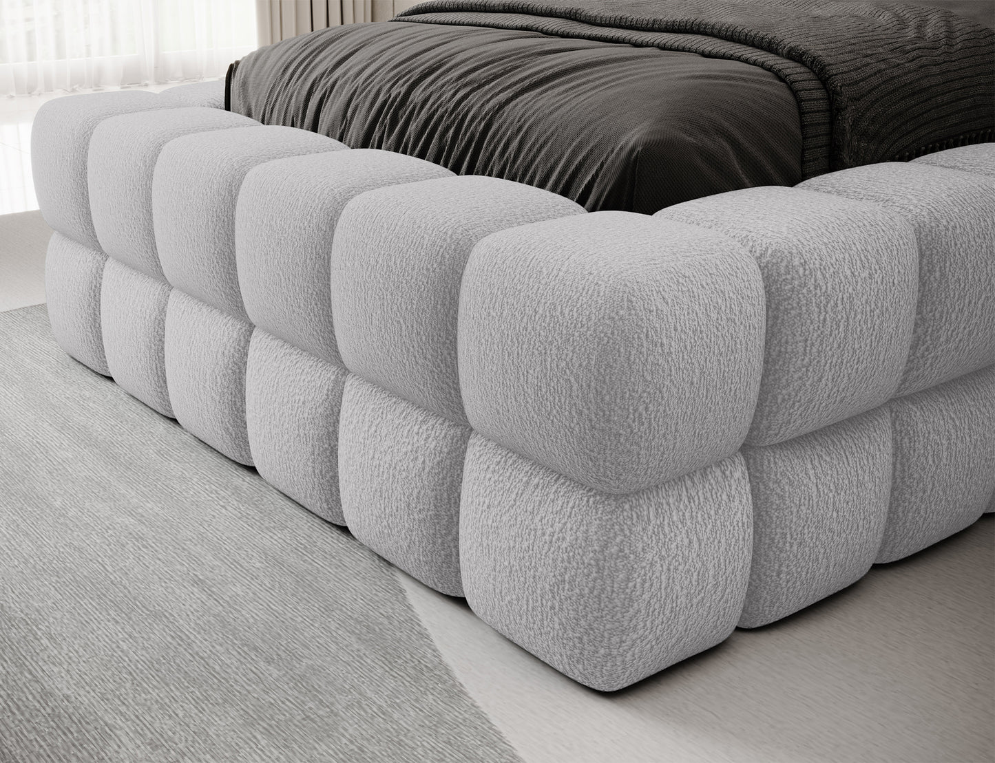 Bok łóżka Dizzle I 90x200 cm w tkaninie Royal 04 szary, zbliżenie na miękką bryłę tapicerowaną pianką z przeszyciami.