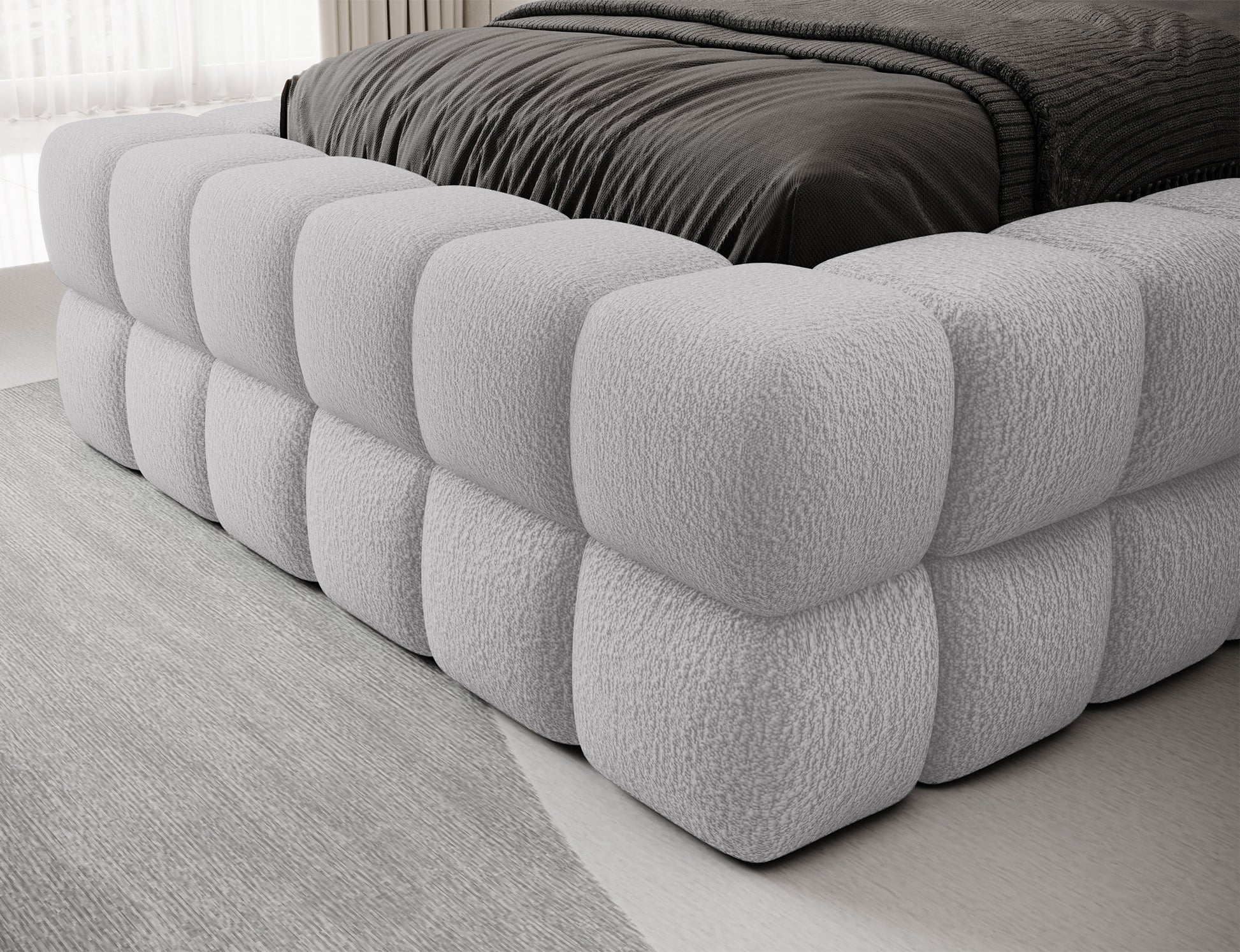 Bok łóżka Dizzle I 90x200 cm w tkaninie Royal 04 szary, zbliżenie na miękką bryłę tapicerowaną pianką z przeszyciami.