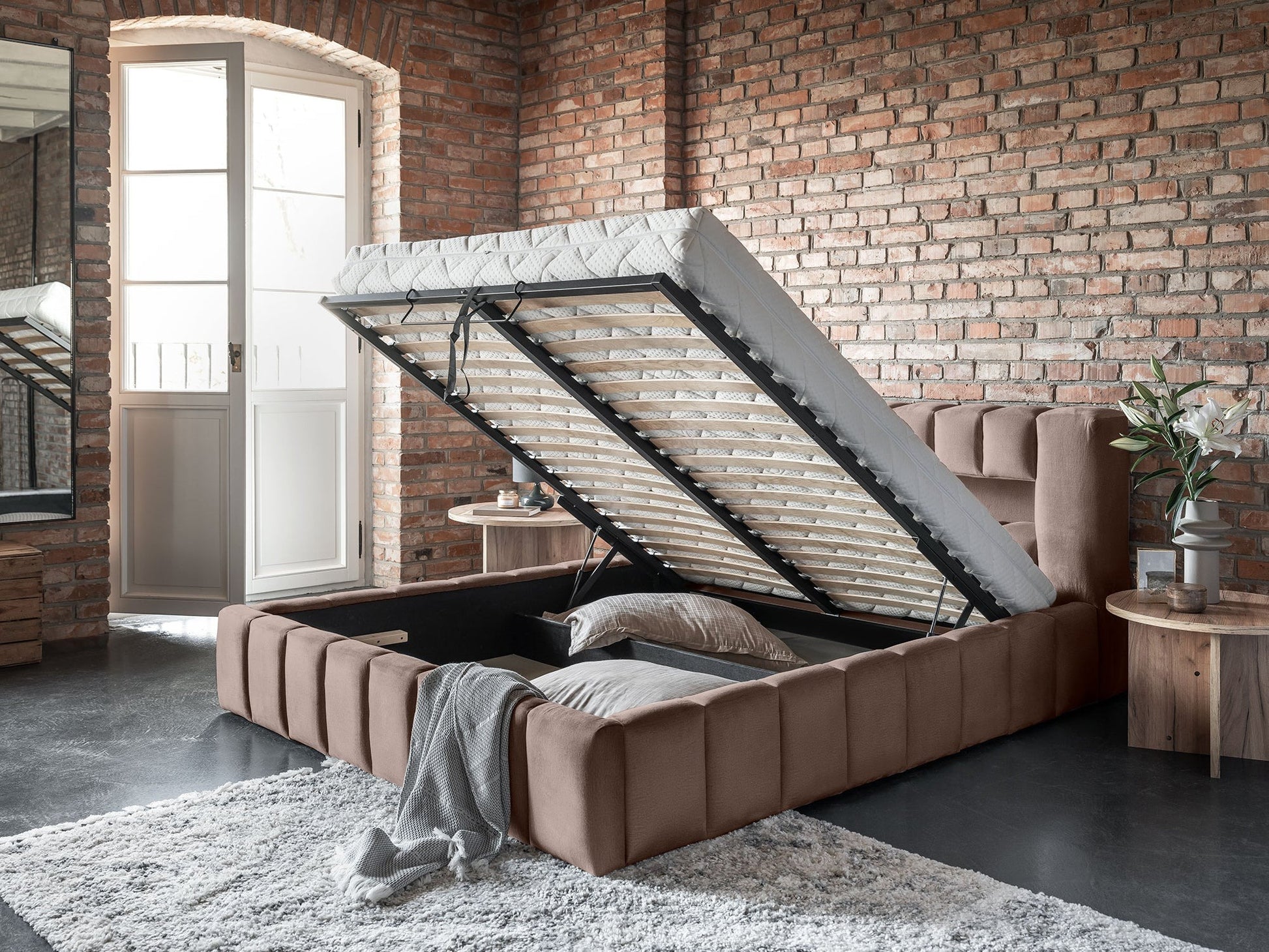 Perspektywa z boku na łóżko Lamica Monolith 09 piaskowy (140×200 cm) ze stelażem uniesionym ku górze, pokazująca pojemny schowek pod materacem.