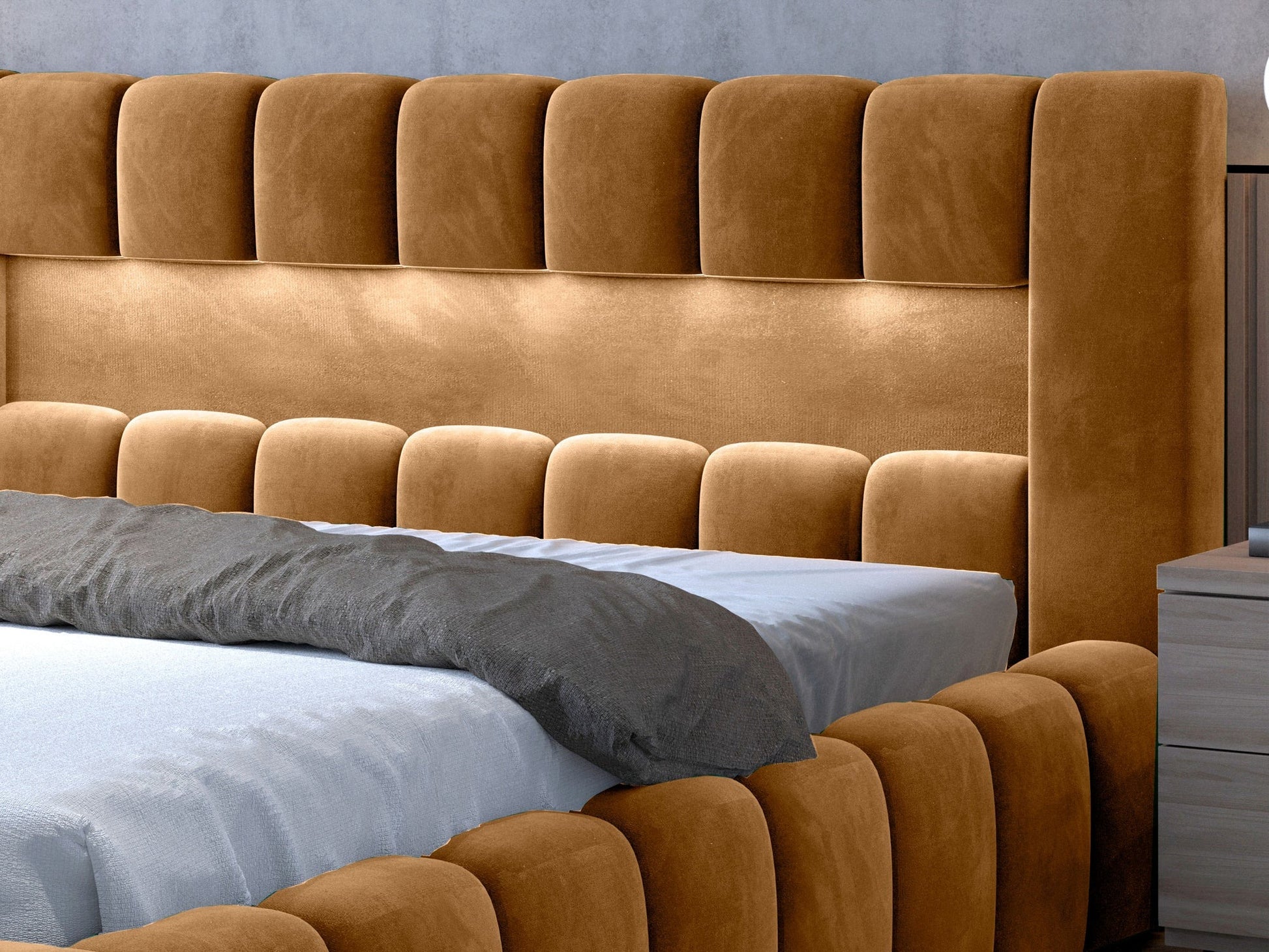 Zbliżenie na pikowane, welurowe wezgłowie i górny fragment ramy łóżka Lamica Monolith 48 miodowy (140 × 200 cm) z widocznym materacem i dyskretnym podświetleniem LED.