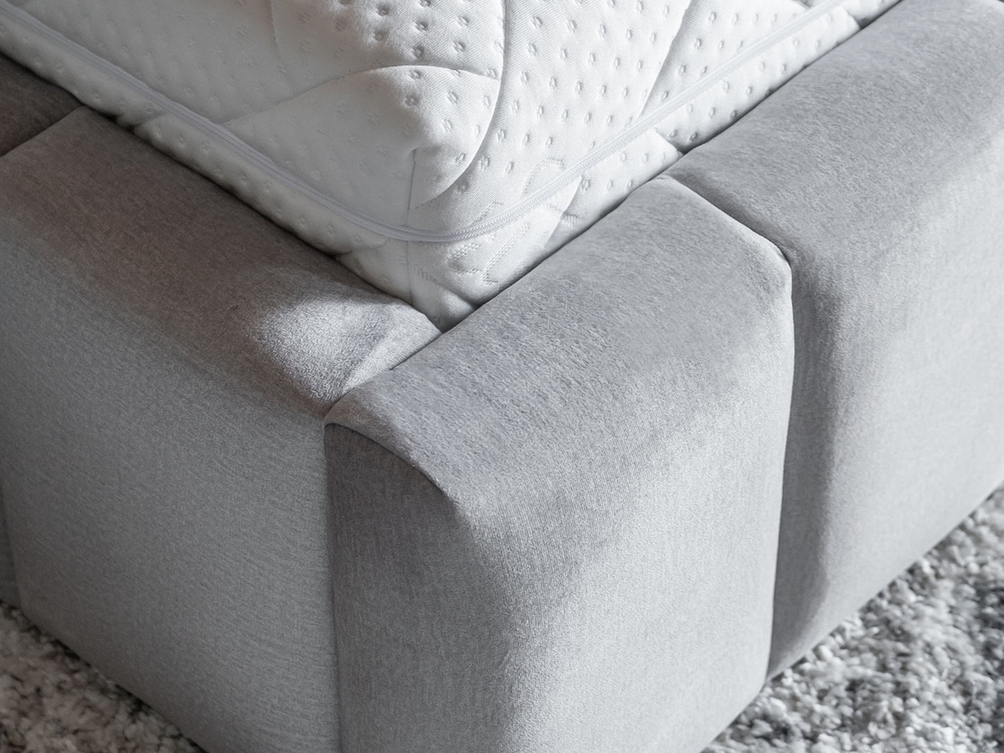 Zbliżenie na miękkie, zaokrąglone moduły dolnej ramy łóżka Lamica Monolith 84 jasnoszary tworzące solidną podstawę.