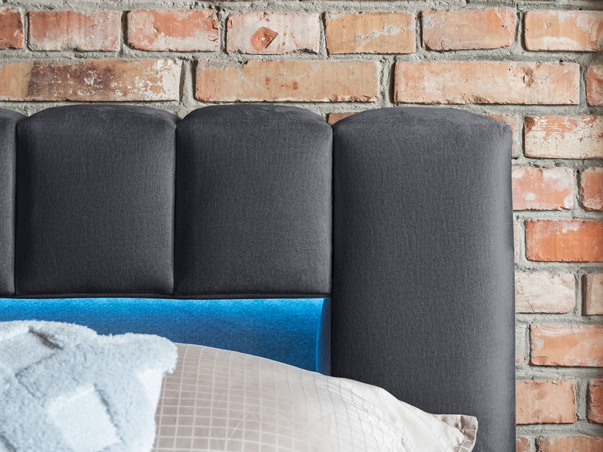 Detale wezgłowia: Zbliżenie na tapicerowane wezgłowie łóżka Monolith 85 szary 140×200 cm z dyskretnym oświetleniem LED w zagłębieniu panelu.