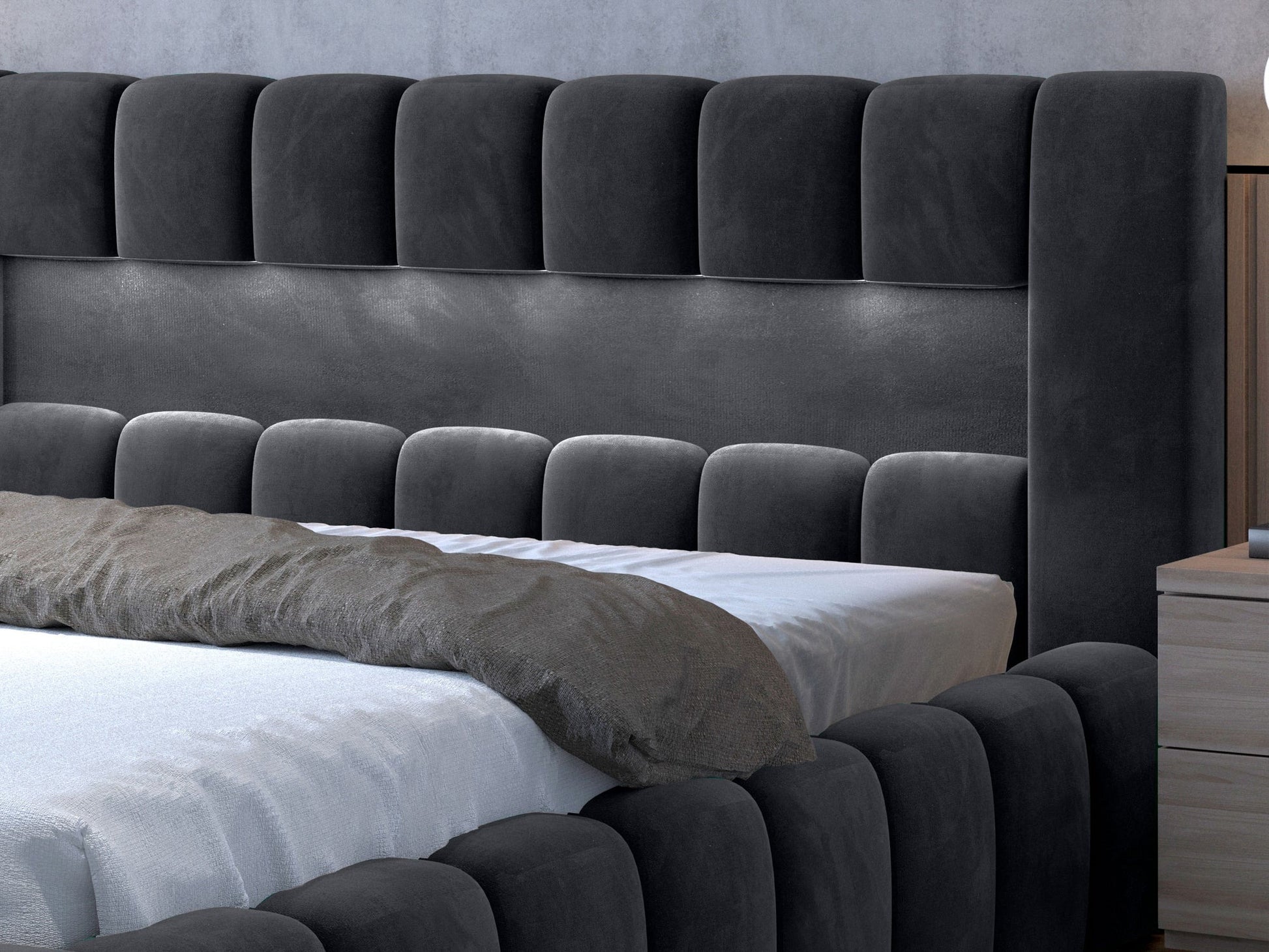 Narożnik ramy: Detal zaokrąglonego narożnika łóżka Monolith 85 szary 140×200 cm, uwypuklający miękką, welurową tkaninę i pikowanie modułów.