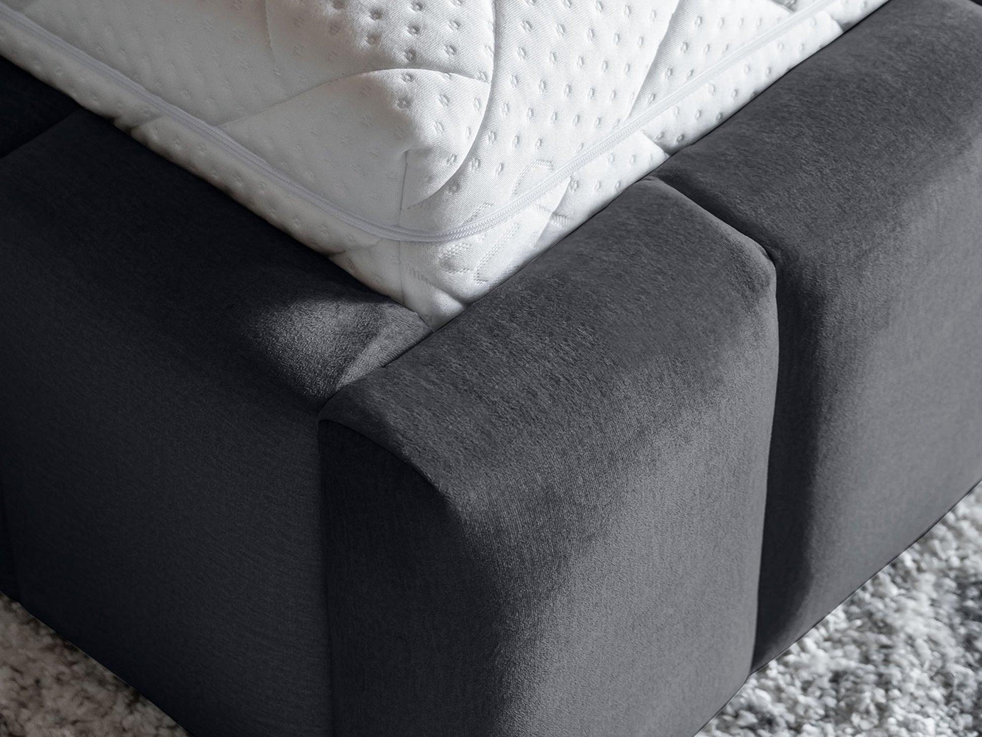 Dolna część ramy: Zbliżenie podstawy łóżka Monolith 85 szary 140×200 cm, ukazujące równomiernie rozmieszczone, prostokątne panele wokół stelaża.