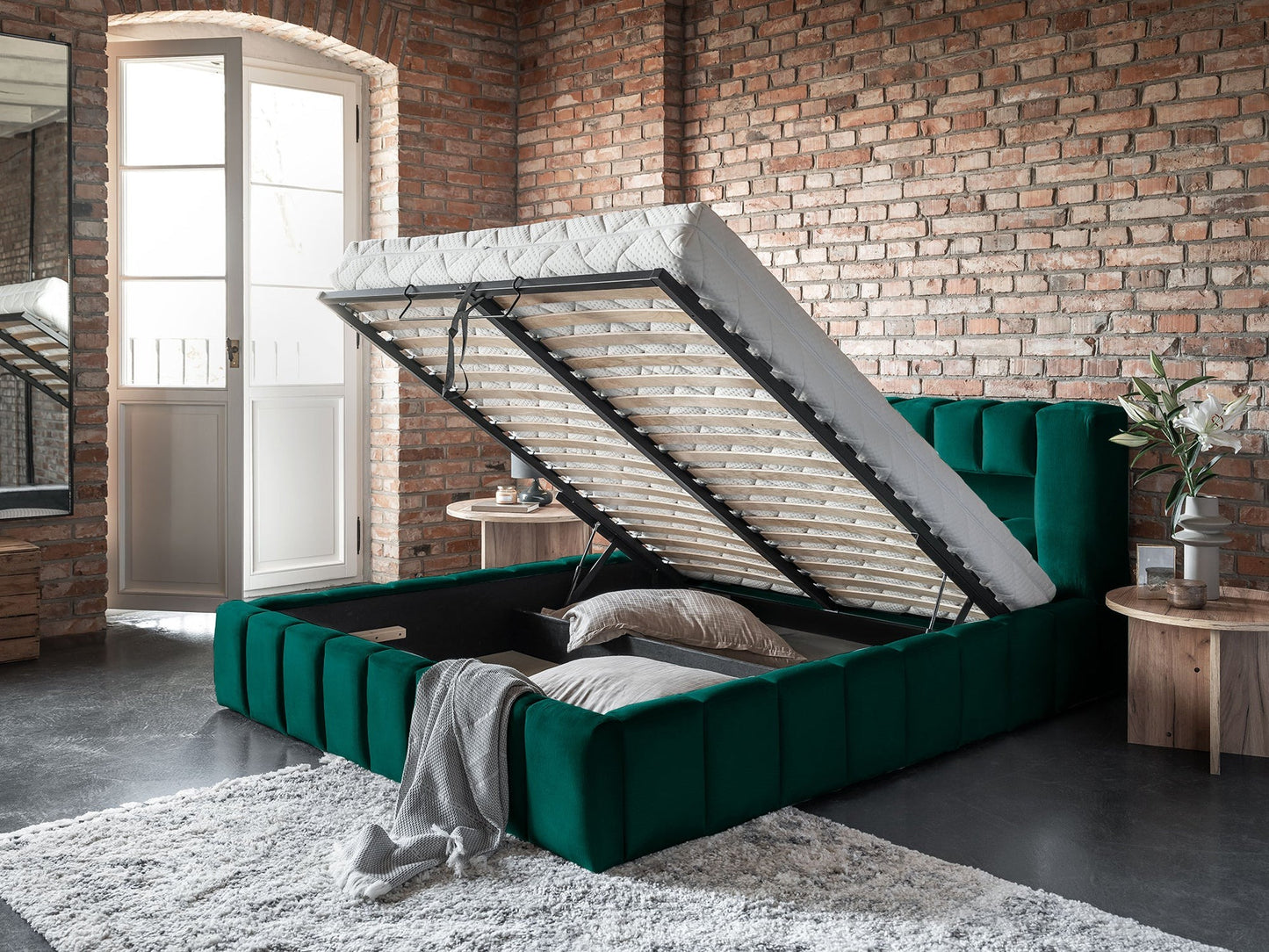 Łóżko Lamica 180x200 cm w kolorze Monolith 37 butelkowozielony z otwartym pojemnikiem na pościel w lofcie z ceglaną ścianą.