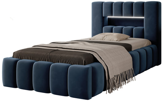 Granatowe tapicerowane łóżko Lamica I Nube 40 (90×200 cm) widziane z boku, z charakterystycznymi, zaokrąglonymi panelami wokół ramy i wezgłowia.