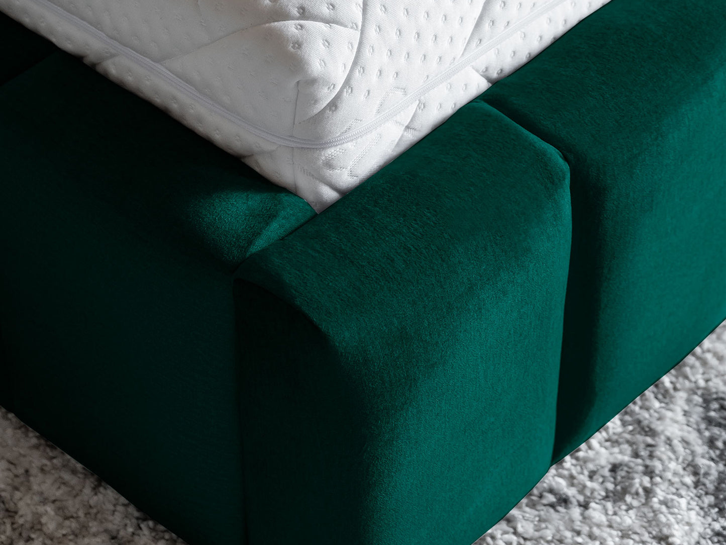 Zbliżenie na narożnik materaca i tapicerowaną ramę podstawy łóżka Lamica II Monolith 37 butelkowozielony.