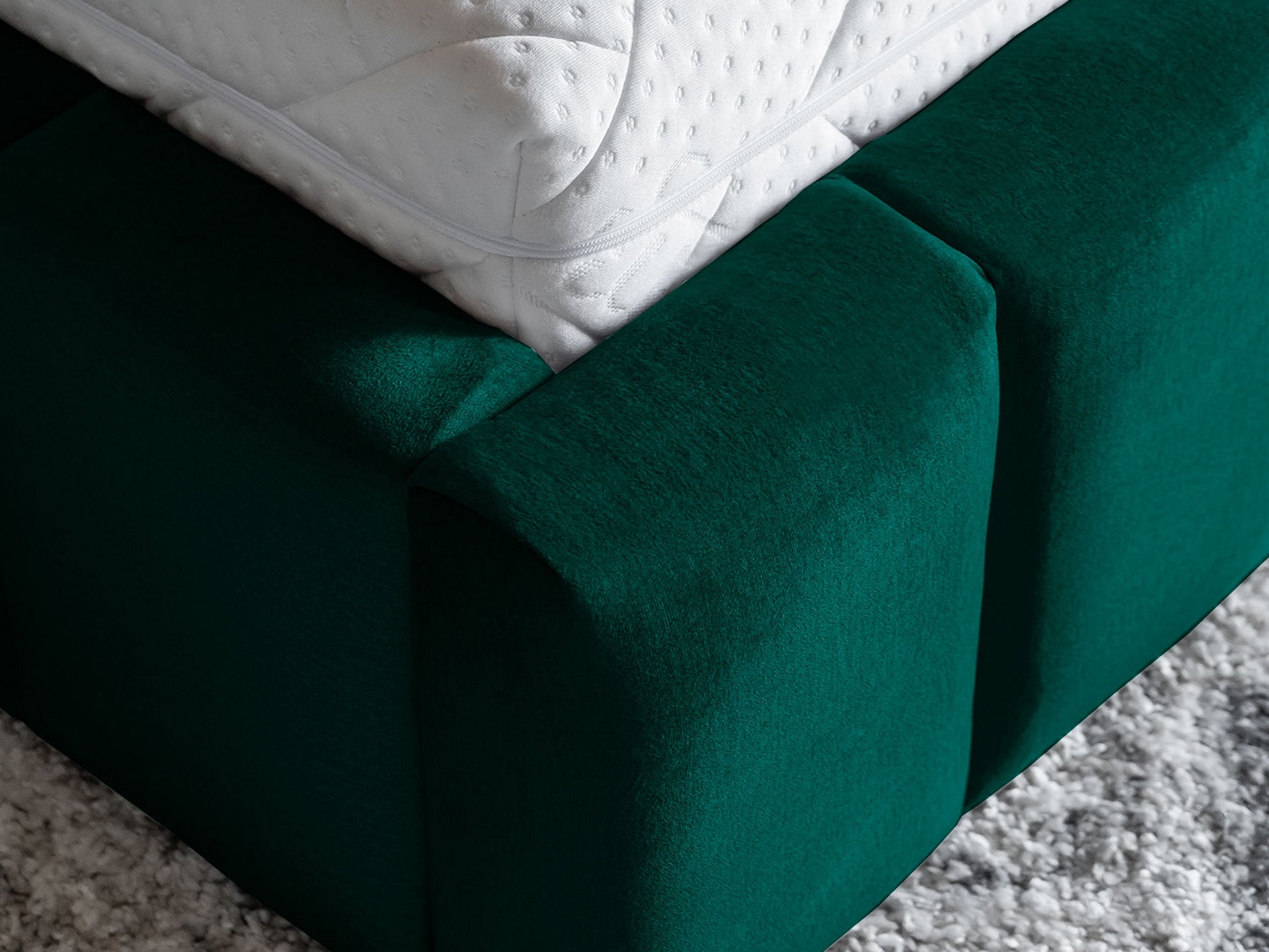 Zbliżenie na narożnik materaca i tapicerowaną ramę podstawy łóżka Lamica II Monolith 37 butelkowozielony.