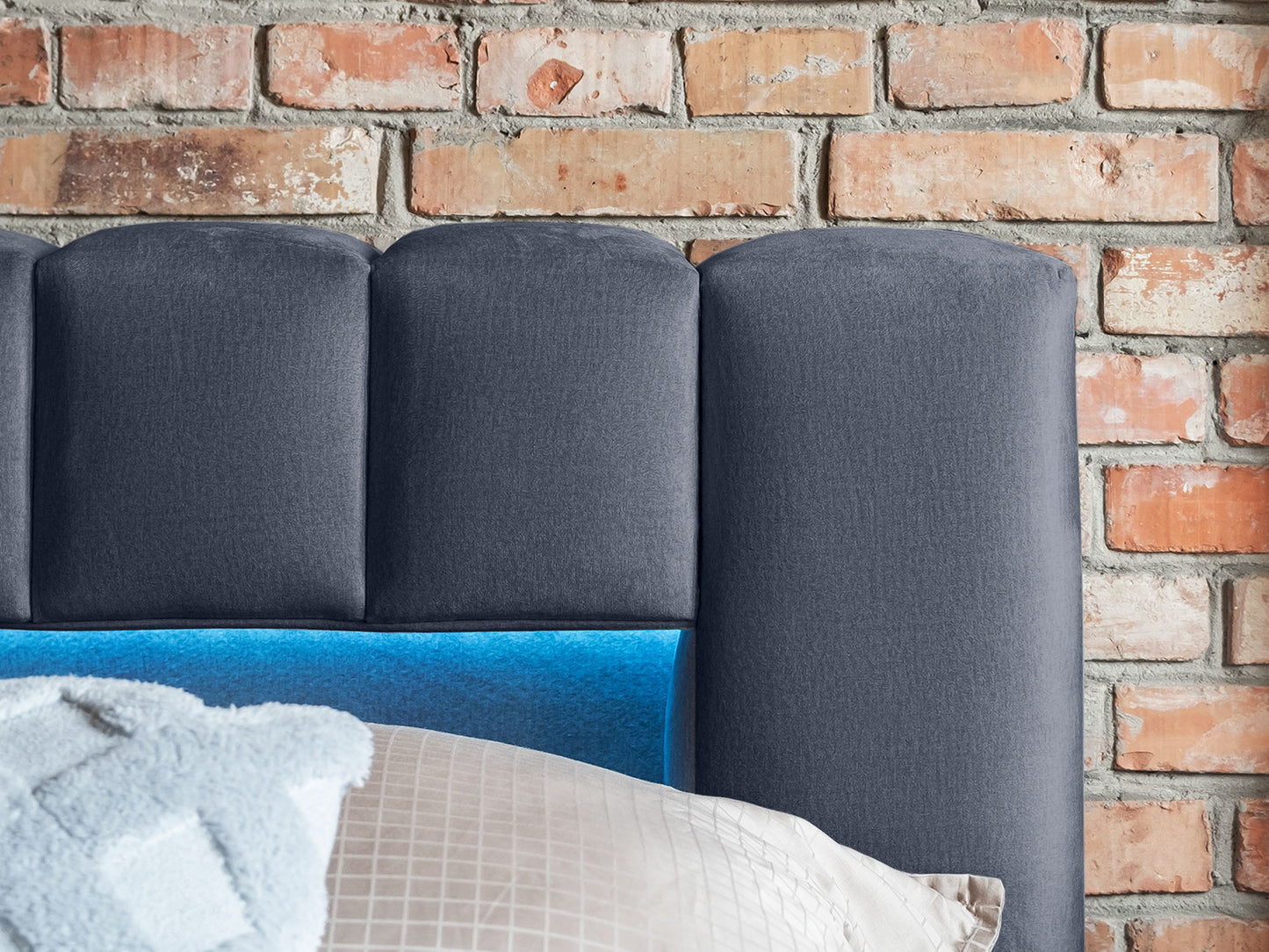 Detal górnej części zagłówka z miękką welurową tapicerką i wbudowanym oświetleniem LED łóżka Lamica II Monolith 97 ciemnoszary.