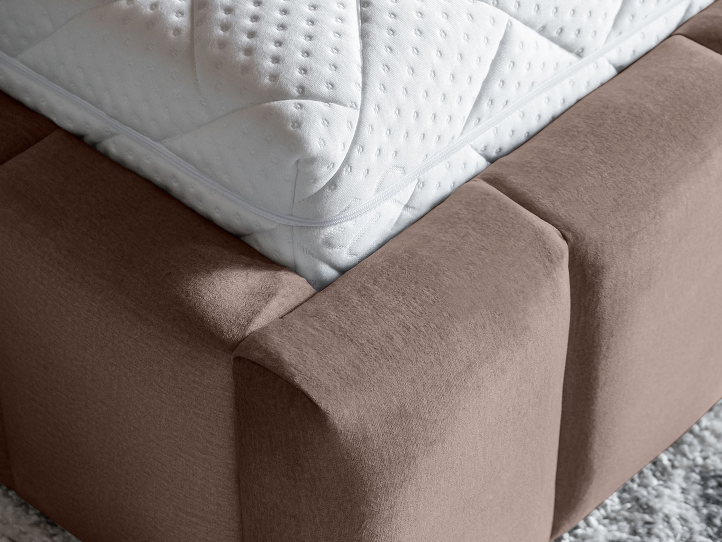 Zbliżenie na róg łóżka Lamica II Monolith 09 piaskowy z materacem, widok detalu tapicerki.