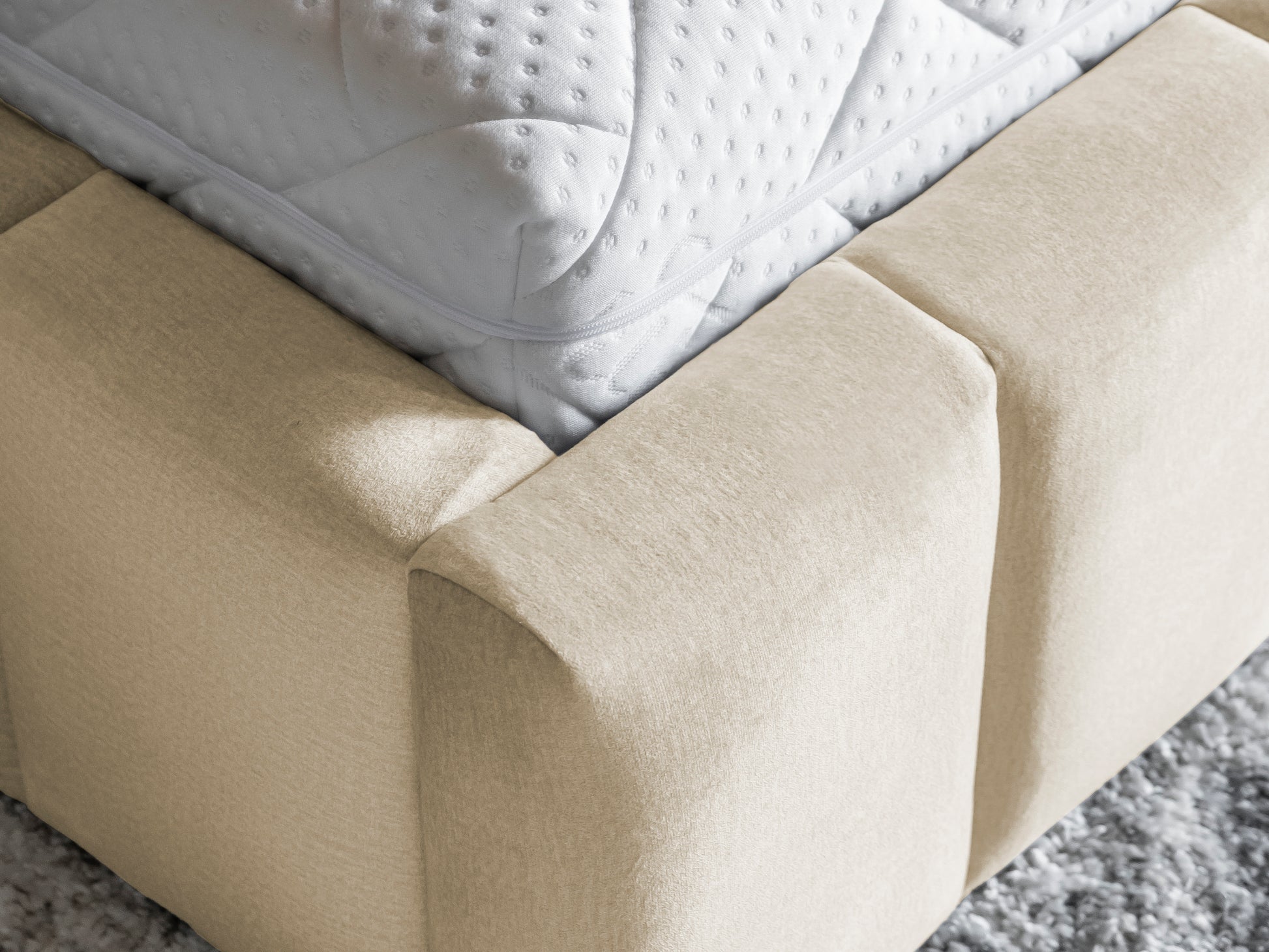 Detal narożnika łóżka Lamica II Monolith 04 – miękka beżowa tapicerka i solidne wykończenie.