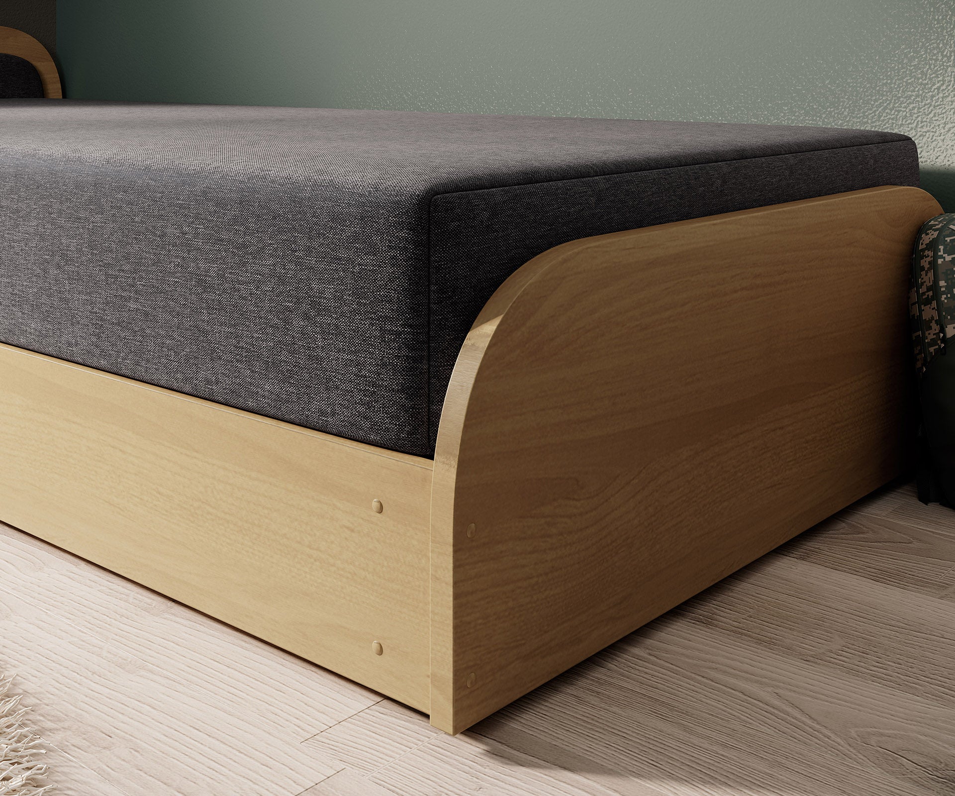 Zbliżenie na dolną część łóżka Parys w tkaninie Sawana 05 ciemnoszary (układ lewy), pokazujące drewnianą podstawę i materiałowy bok materaca.