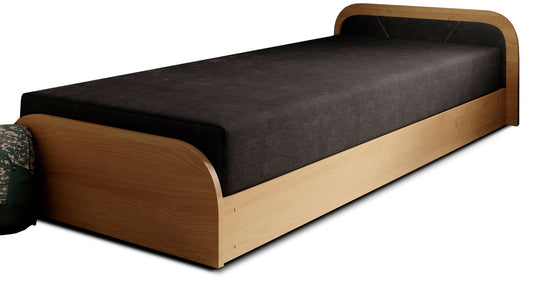 Łóżko Parys w tkaninie Sawana 14 czarny, układ prawy, na białym tle z jasnobrzozową ramą i czarnym materacem, obok plecaka moro.