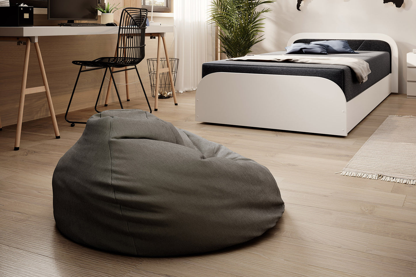 Perspektywa wnętrza z pufą w pierwszym planie i łóżkiem Parys I Sawana 05 ciemnoszary, prawy układ, obok biurka i krzesła.