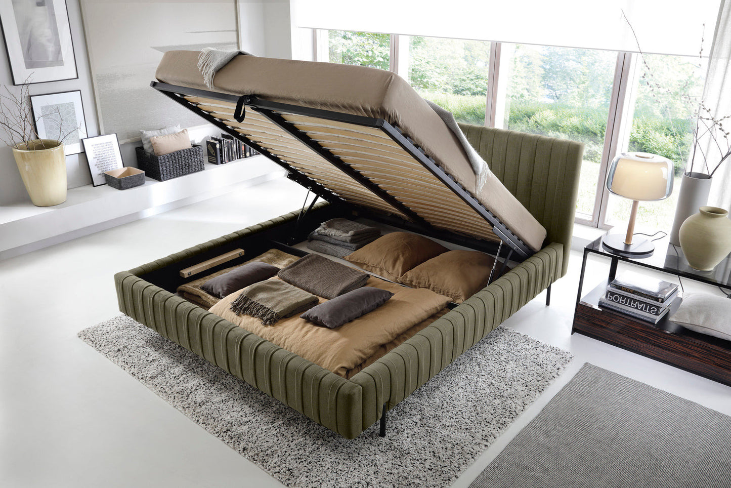 Łóżko Plissa 140×200 w obiciu Nube 33 jasnozielonym ze stelażem podniesionym do góry, odsłaniającym pojemny schowek na pościel, ustawione na jasnoszarym dywanie.