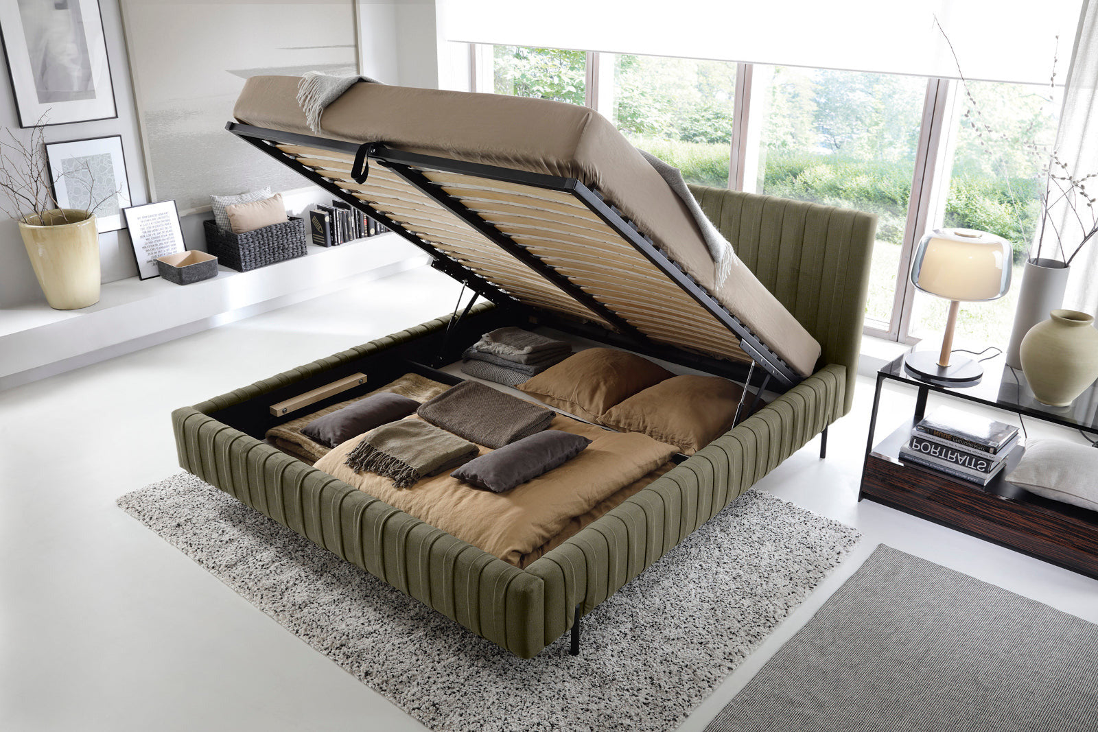 Łóżko Plissa 140×200 w obiciu Nube 33 jasnozielonym ze stelażem podniesionym do góry, odsłaniającym pojemny schowek na pościel, ustawione na jasnoszarym dywanie.