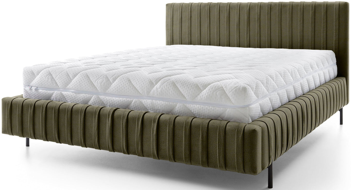 Łóżko Plissa 140×200 w welwetowym obiciu Nube 33 jasnozielonym z białym, pikowanym materacem na smukłych czarnych nogach, widok z przodu na białym tle.