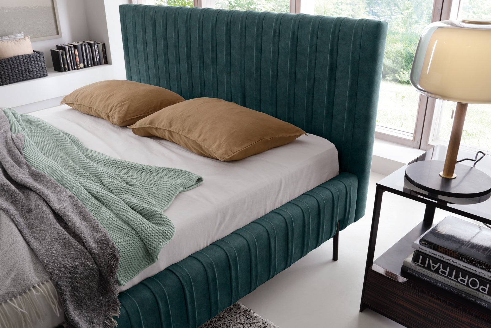 Zbliżenie na wezgłowie i materac łóżka Plissa 180×200 w ciemnozielonej tkaninie Relax 38 z dwoma brązowymi poduszkami obok lampki nocnej.