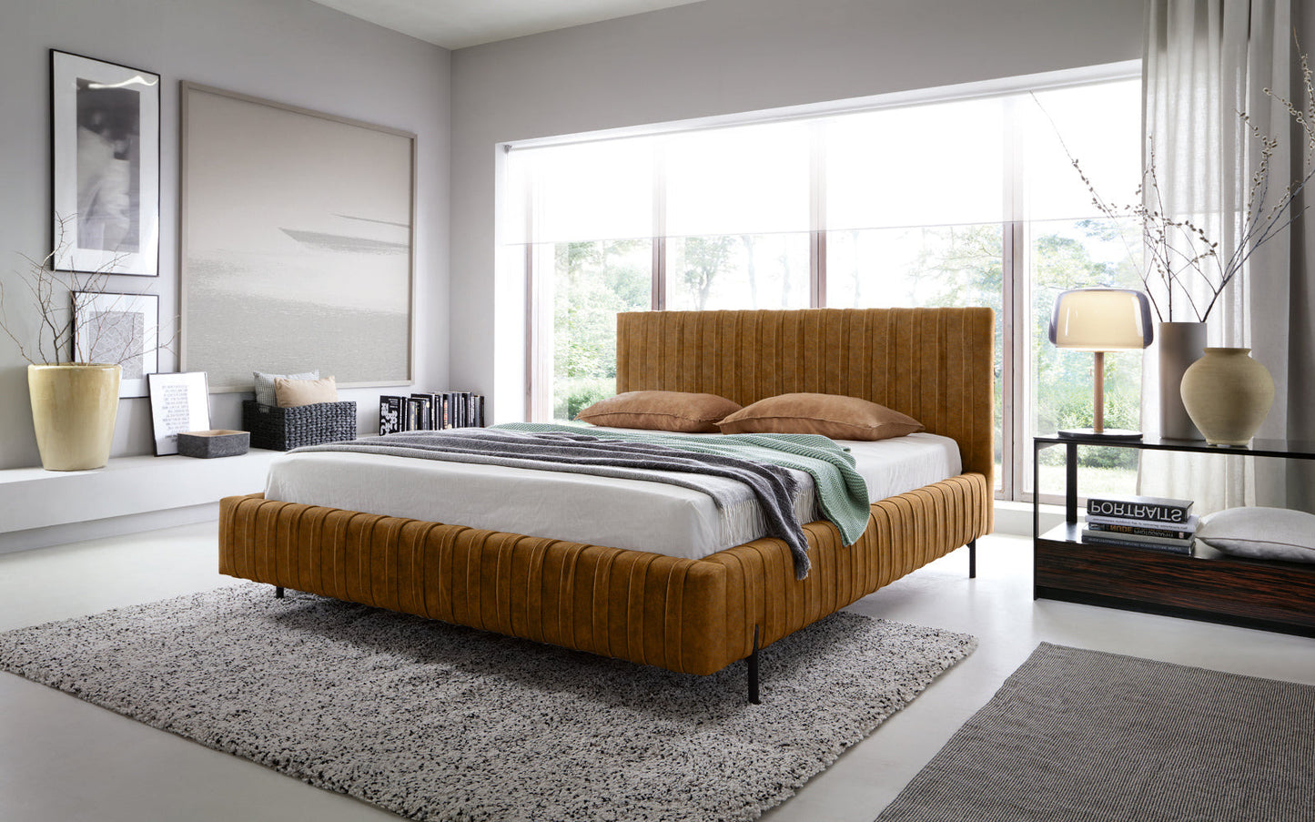 Łóżko Plissa 140×200 w kolorze Relax 45 żółty ustawione na dwuwarstwowym dywanie przed dużym oknem w nowoczesnej sypialni, ozdobione narzutą i poduszkami.