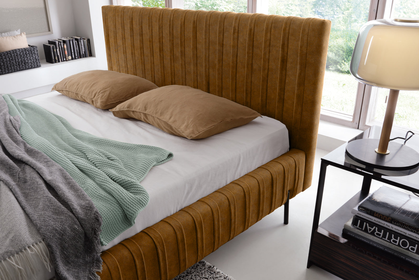 Zbliżenie na wysokie, pikowane wezgłowie łóżka Plissa 160×200 w żółtej tkaninie Relax 45 z dwoma brązowymi poduszkami i lampką nocną.