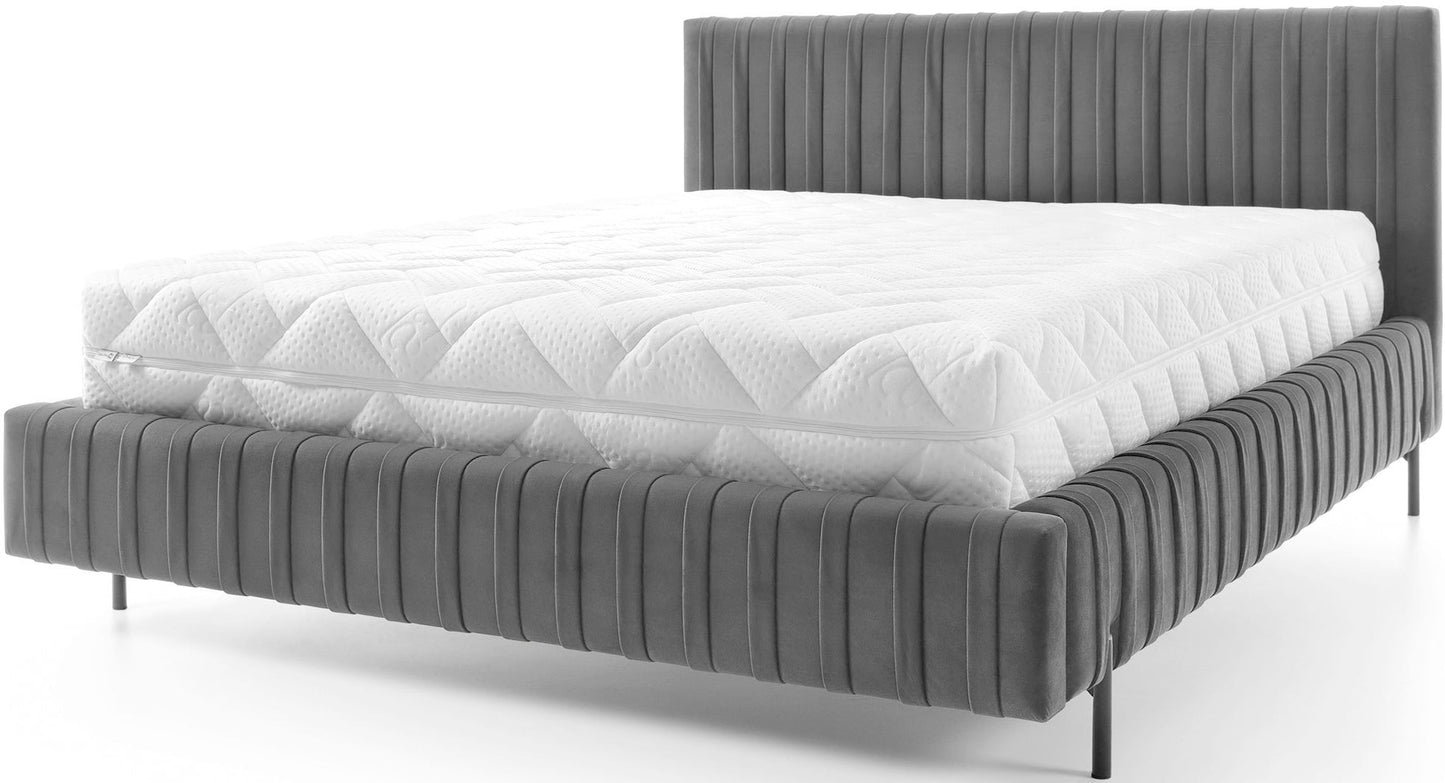 Frontowy widok łóżka Plissa 160×200 Velvetmat 04 szarego z pikowanym białym materacem na cienkich, czarnych nóżkach, eksponujący karbowaną tapicerkę ramy.