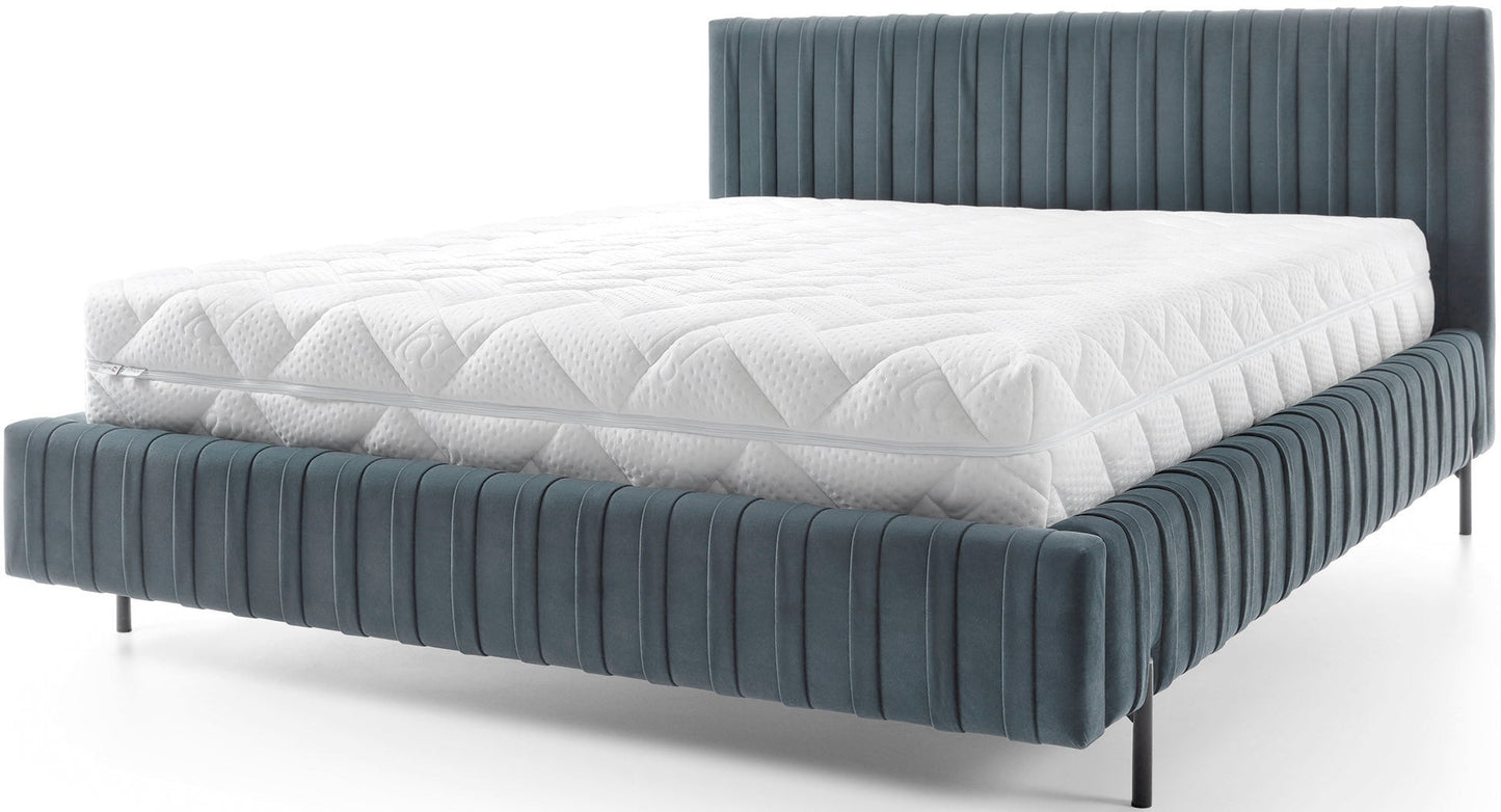 Tapicerowane łóżko Plissa w jasnoniebieskim welwetu Velvetmat 100 na smukłych czarnych nogach, widok z przodu na białym tle.